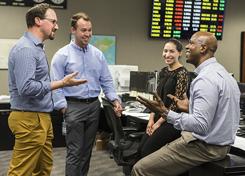 Smiling employees engaged in work discussion on Valero trading floor