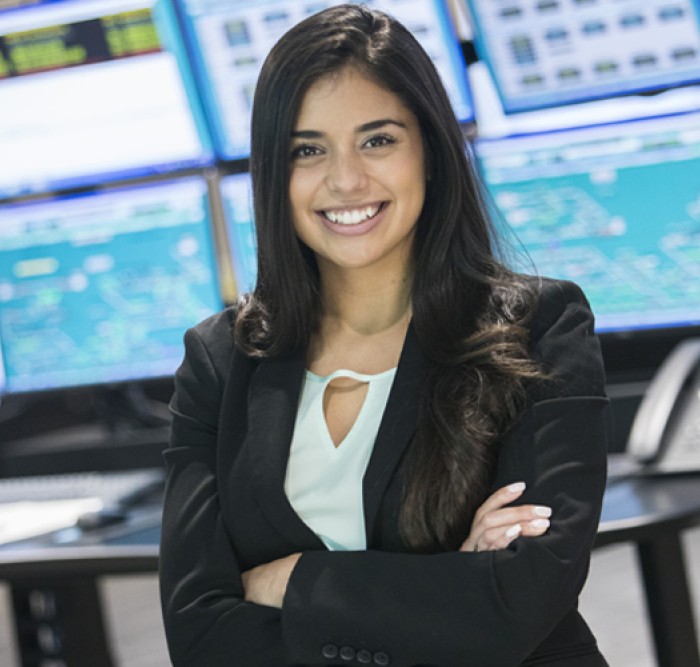 Woman smiling in front of screens with arms folded