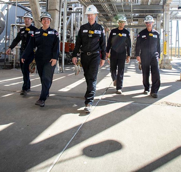 Team of five Valero employees walking through the Three Rivers refinery, surrounded by equipment.