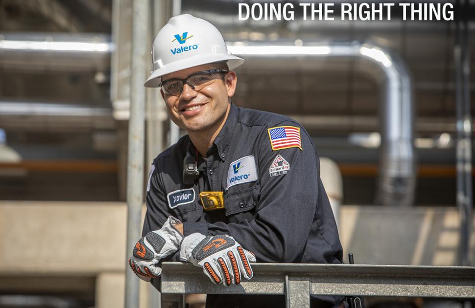 Refinery engineer smiling in hardhat and safety gear on a unit platform